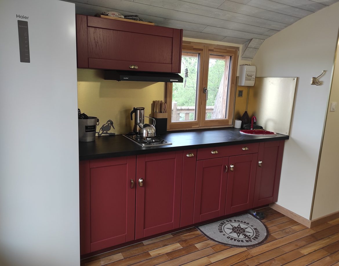 Cuisine moderne dans un hébergement insolite en Limousin, avec meubles rouges élégants.