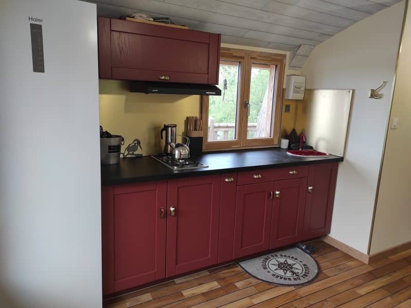 Cuisine moderne dans un hébergement insolite en Limousin, avec meubles rouges élégants.