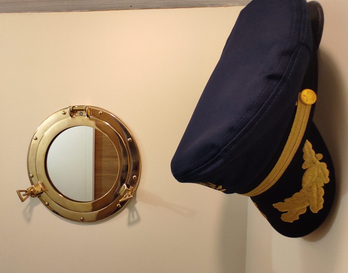 Hébergement insolite à Limousin : cabine de bateau avec miroir rond et chapeau de capitaine.