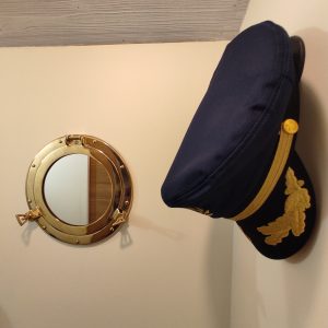 Hébergement insolite à Limousin : cabine de bateau avec miroir rond et chapeau de capitaine.