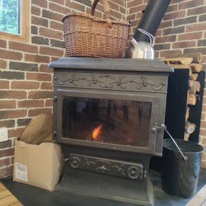 Hébergement insolite à Limousin : poêle à bois vintage avec panier en osier.