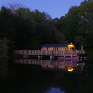 Cabane flottante au Limousin, illuminée, reflétée sur leau paisible.