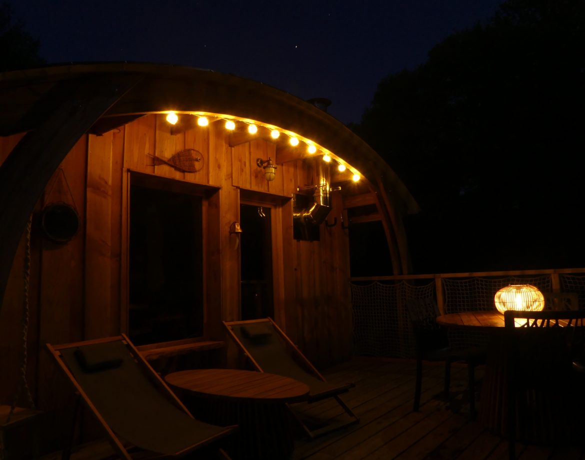 Cabane en bois à Limousin, éclairage chaleureux et terrasse accueillante.