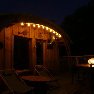 Cabane en bois à Limousin, éclairage chaleureux et terrasse accueillante.