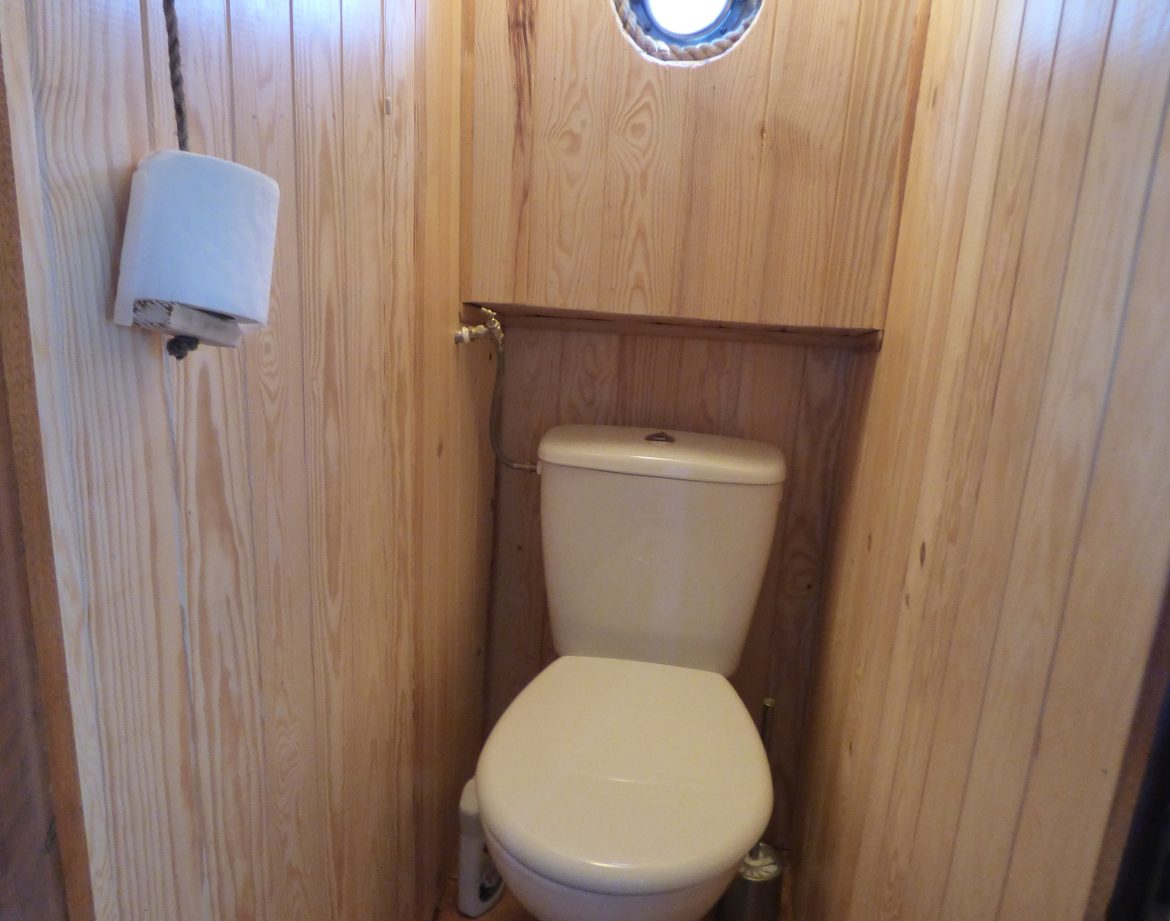 Toilettes en bois dans un hébergement insolite en Auvergne, ambiance chaleureuse.