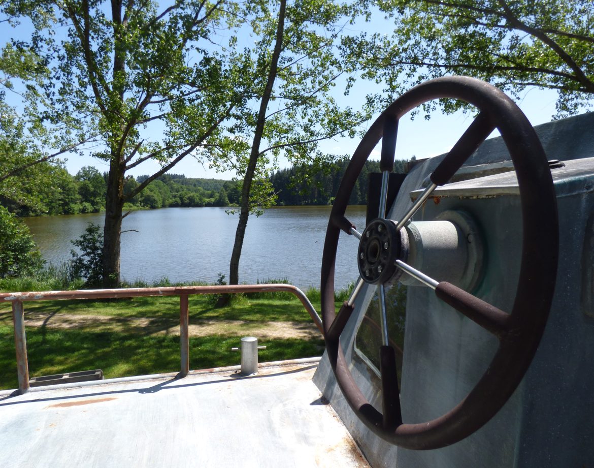 Hébergement insolite en péniche avec vue sur le lac et verdure environnante.