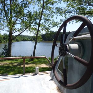 Hébergement insolite en péniche avec vue sur le lac et verdure environnante.