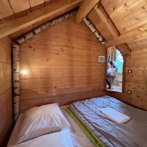 Cabane en bois chaleureuse avec murs en bois naturel et lit douillet.