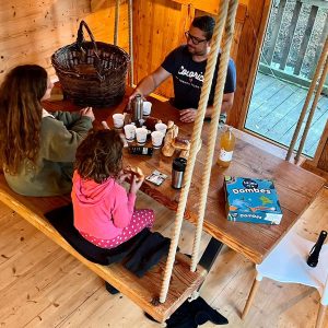 Cabane suspendue en bois, famille partageant un moment convivial autour dune table.