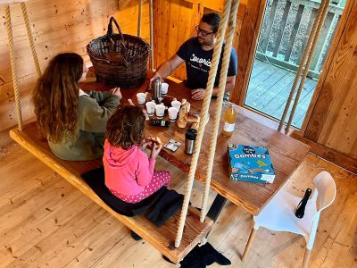 Cabane suspendue en bois, famille partageant un moment convivial autour dune table.