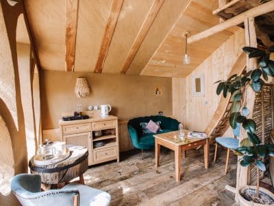 Hébergement insolite en Bretagne : intérieur en bois avec un canapé vert et des détails naturels.
