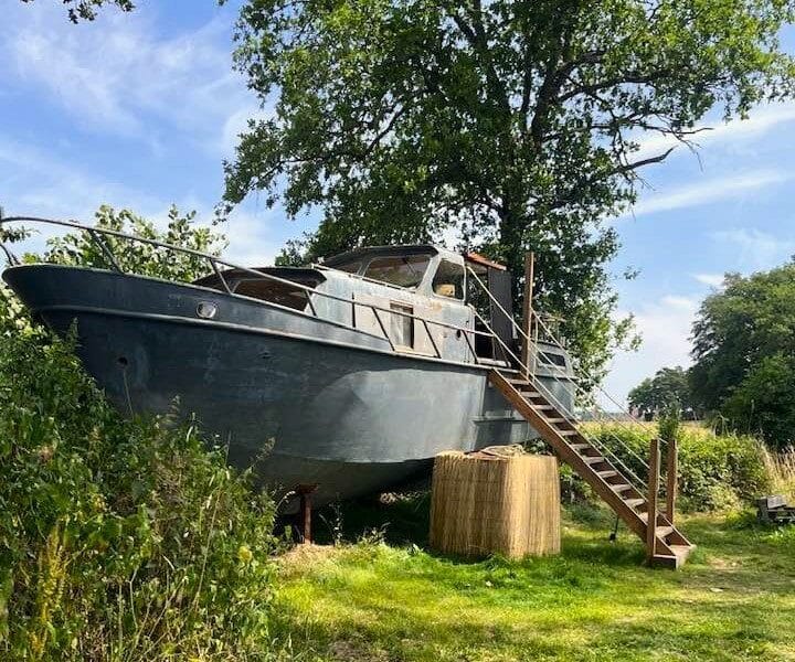 Hébergement insolite en bateau à Auvergne, perché sur pilotis avec un accès en escaliers.