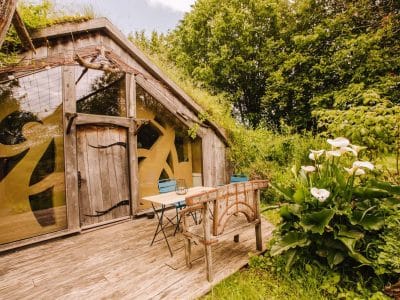 Hébergement insolite en Bretagne : cabane en bois avec grandes fenêtres et verdure environnante.