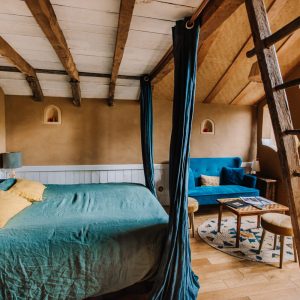 Hébergement insolite en Bretagne : chambre chaleureuse avec lit douillet et poutres apparentes.