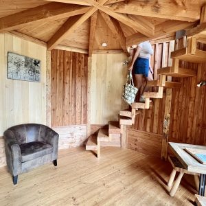 Cabane en bois avec escalier en colimaçon et coin salon cosy.
