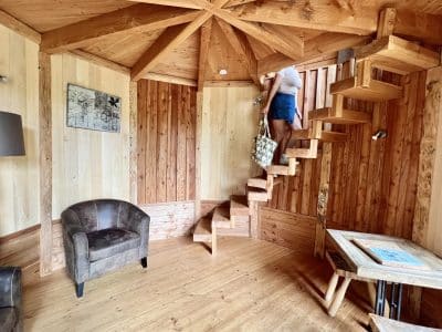 Cabane en bois avec escalier en colimaçon et coin salon cosy.