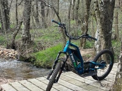 Vélo électrique sur un pont en bois, entouré de verdure en Auvergne-Rhône-Alpes.
