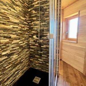 Douche moderne en pierre dans un hébergement insolite en Auvergne-Rhône-Alpes.