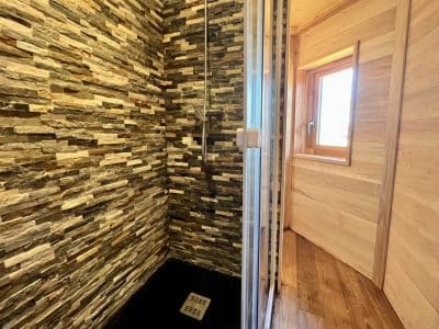 Douche moderne en pierre dans un hébergement insolite en Auvergne-Rhône-Alpes.