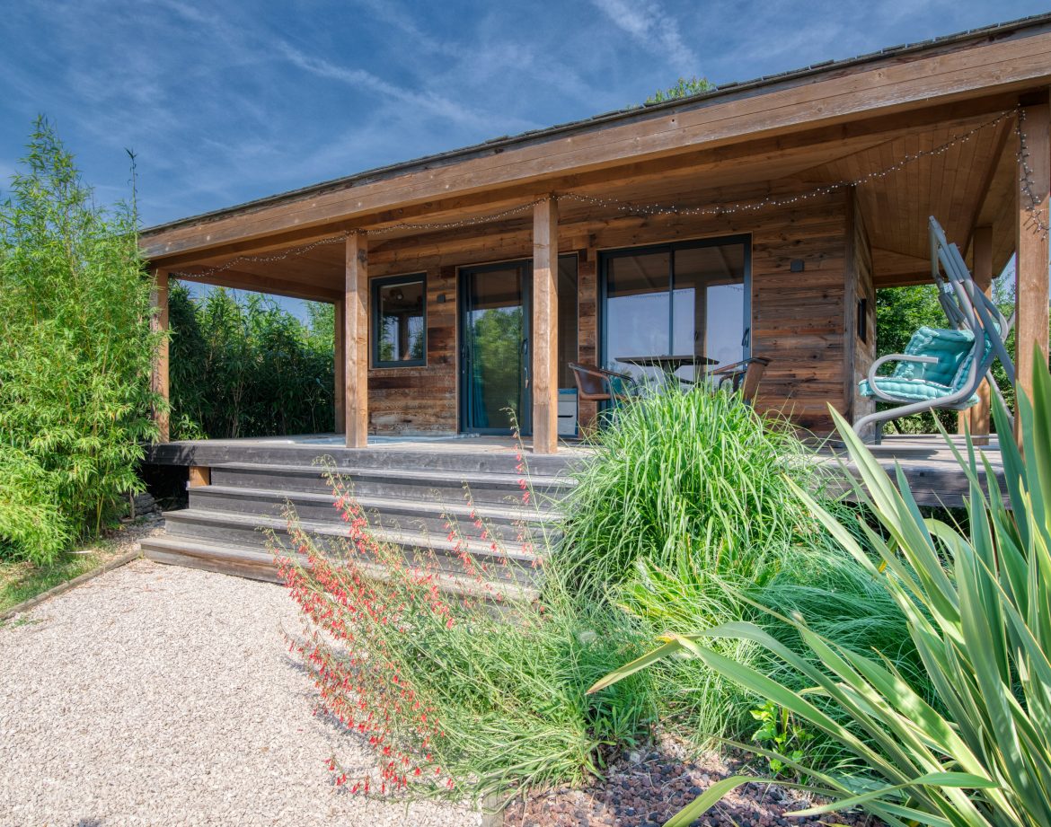 Cabane en bois avec terrasse, entourée de verdure luxuriante à Languedoc-Roussillon.