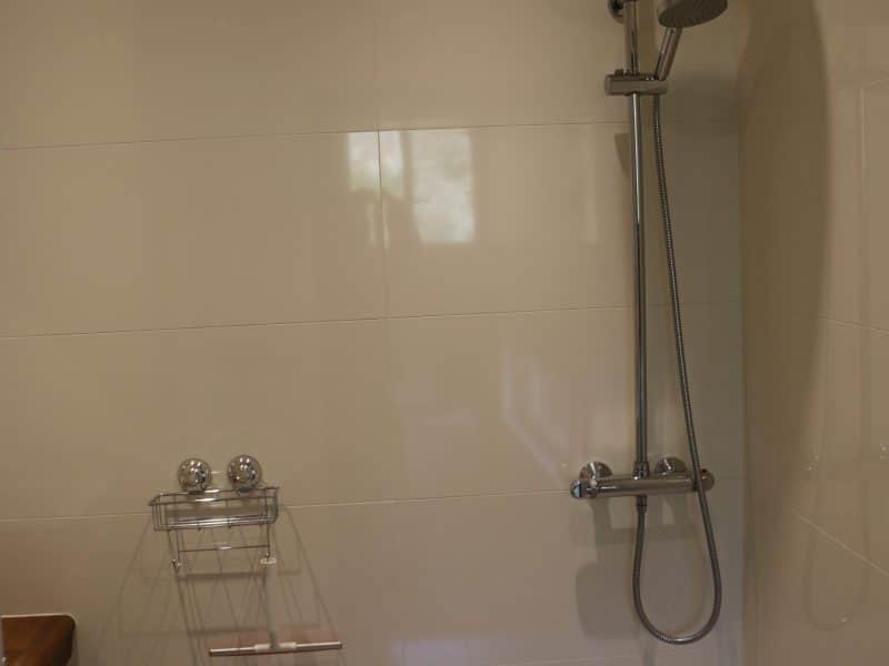 Salle de bain moderne dun hébergement touristique, avec douche à litalienne et carrelage en galets.