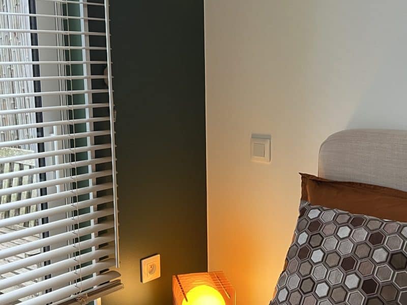 Chambre moderne avec lit confortable et lampe chaleureuse, ambiance apaisante.