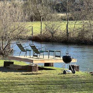 Hébergement insolite en Bourgogne : plateforme au bord de leau avec chaises et barbecue.
