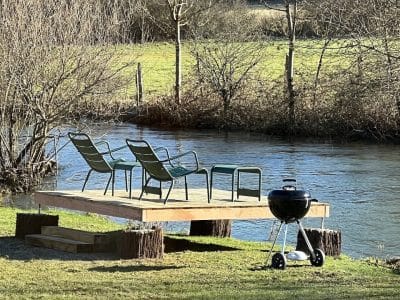 Hébergement insolite en Bourgogne : plateforme au bord de leau avec chaises et barbecue.