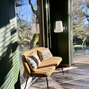 Hébergement insolite en Bourgogne : un cocon moderne avec fauteuil coloré et vue sur la nature.