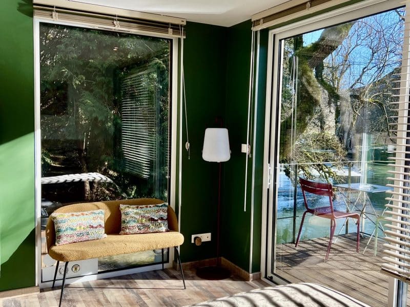 Chambre moderne avec murs verts, vue sur le jardin et mobilier cosy.