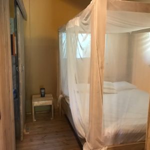 Chambre en bois avec lit à baldaquin, ambiance cosy et naturelle. Hébergement insolite.