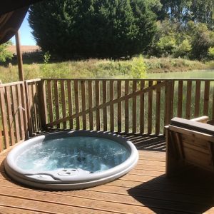 Hébergement insolite en tente avec jacuzzi sur une terrasse en bois, vue sur la nature.