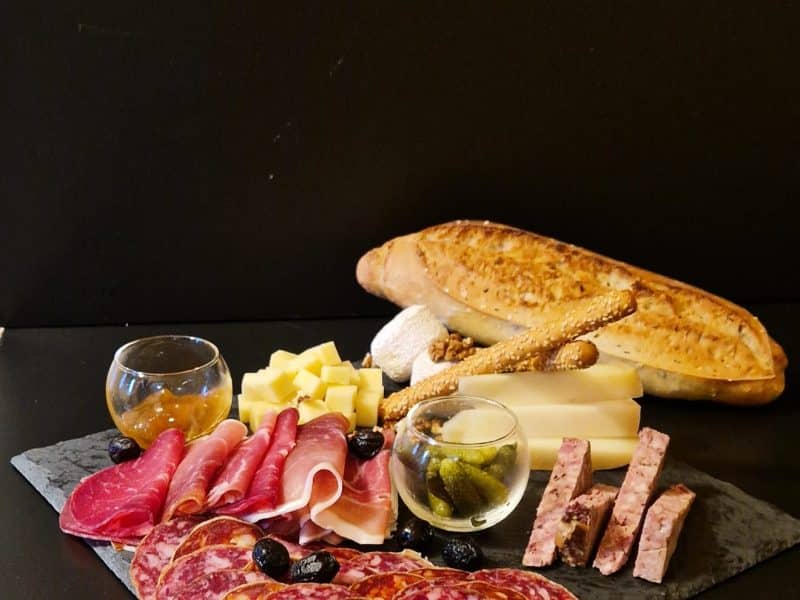 Plateau de charcuterie avec fromages et pain, idéal pour un séjour gourmand.
