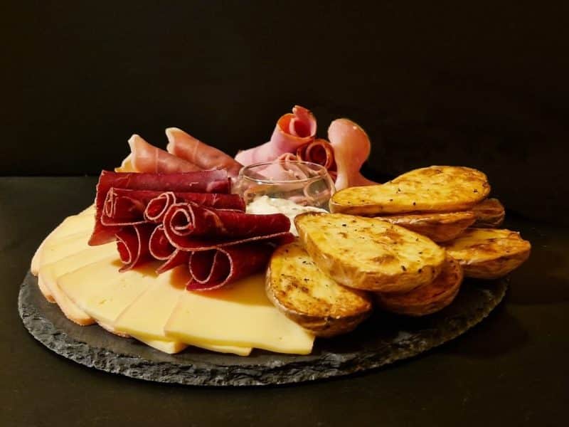 Plateau de charcuterie et fromages, accompagné de pommes de terre rôties.