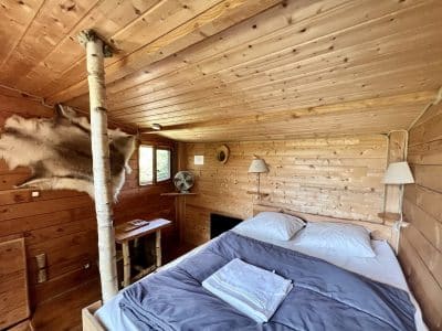 Cabane en bois cosy en Auvergne-Rhône-Alpes, avec lit douillet et décor naturel.