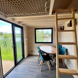 Cabane moderne au bord de leau, avec un coin repas et une mezzanine.