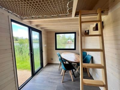 Cabane moderne au bord de leau, avec un coin repas et une mezzanine.