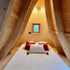Cabane en bois cosy, intérieur chaleureux avec murs en bois et coussins colorés.