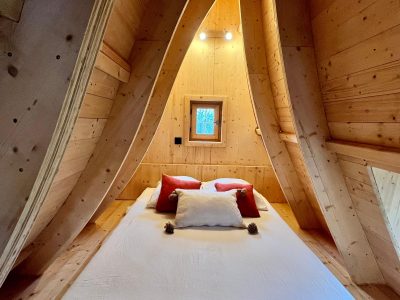 Cabane en bois cosy, intérieur chaleureux avec murs en bois et coussins colorés.