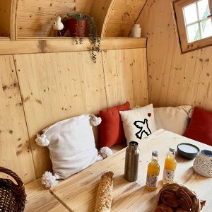 Hébergement insolite en Auvergne-Rhône-Alpes, intérieur en bois chaleureux avec coussins.