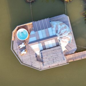 Cabane flottante avec jacuzzi, entourée deau et de verdure en Auvergne-Rhône-Alpes.