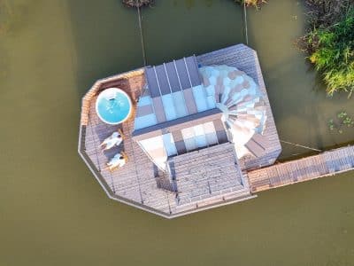 Cabane flottante avec jacuzzi, entourée deau et de verdure en Auvergne-Rhône-Alpes.