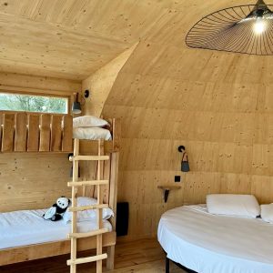 Hébergement insolite en bois en Auvergne-Rhône-Alpes avec lit rond et échelle.