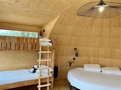 Hébergement insolite en bois en Auvergne-Rhône-Alpes avec lit rond et échelle.
