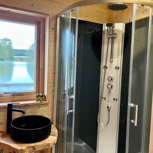 Douche moderne en bois dans un hébergement insolite au bord dun lac en Auvergne-Rhône-Alpes.