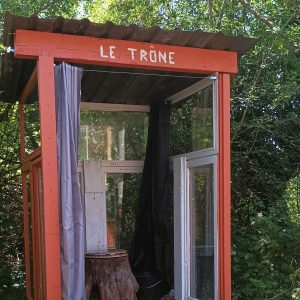 Hébergement insolite Le Trône en bois, avec des fenêtres et un décor naturel verdoyant.