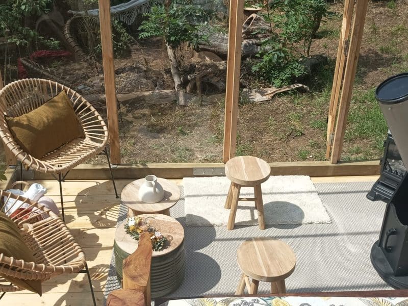 Hébergement insolite : véranda avec télescope, fauteuils confortables et plantes.