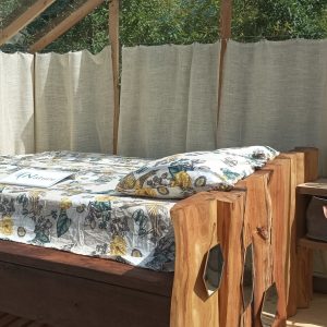 Cabane en bois avec lit confortable et vue sur la nature, ambiance chaleureuse.