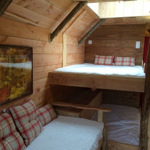 Cabane en bois avec lit en mezzanine et décor chaleureux en bois.