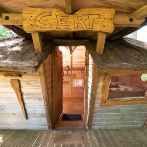 Cabane dans les arbres en Auvergne-Rhône-Alpes, avec un toit en chaume et une entrée accueillante.